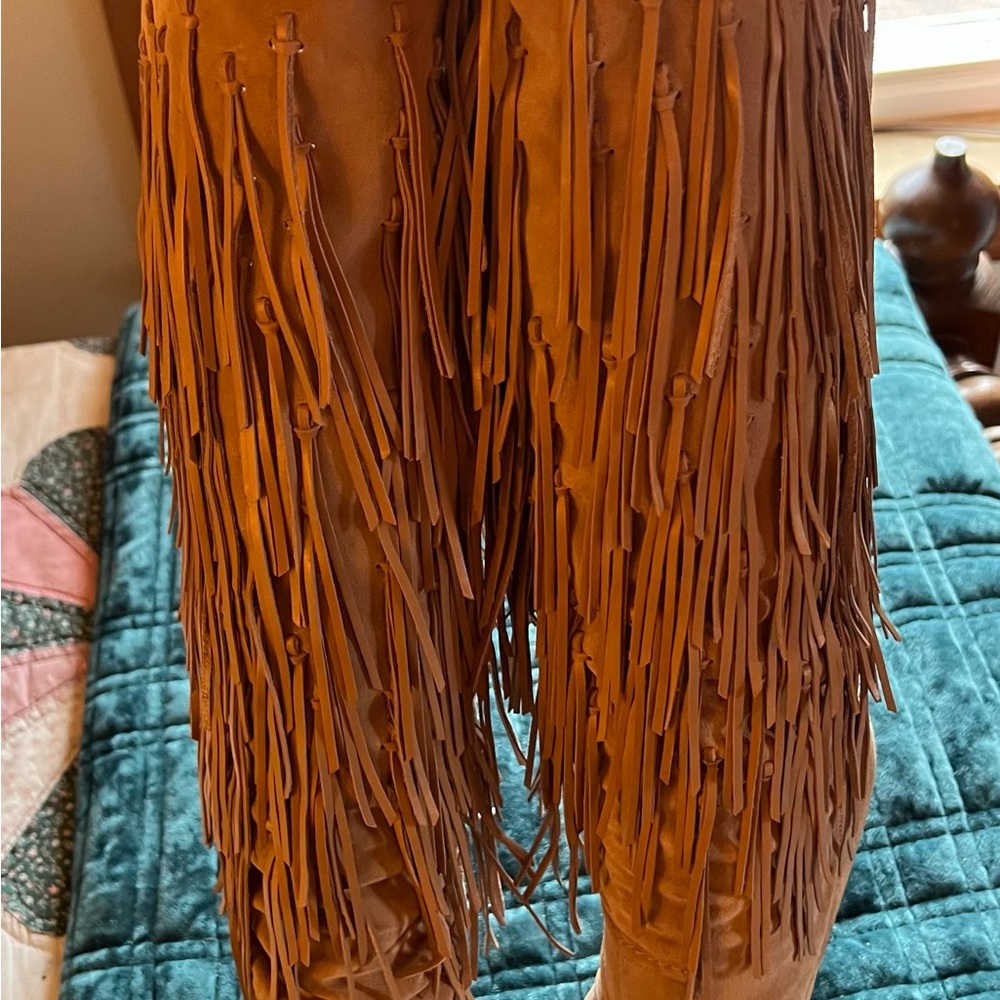 Tan knee high suede fringed boots.